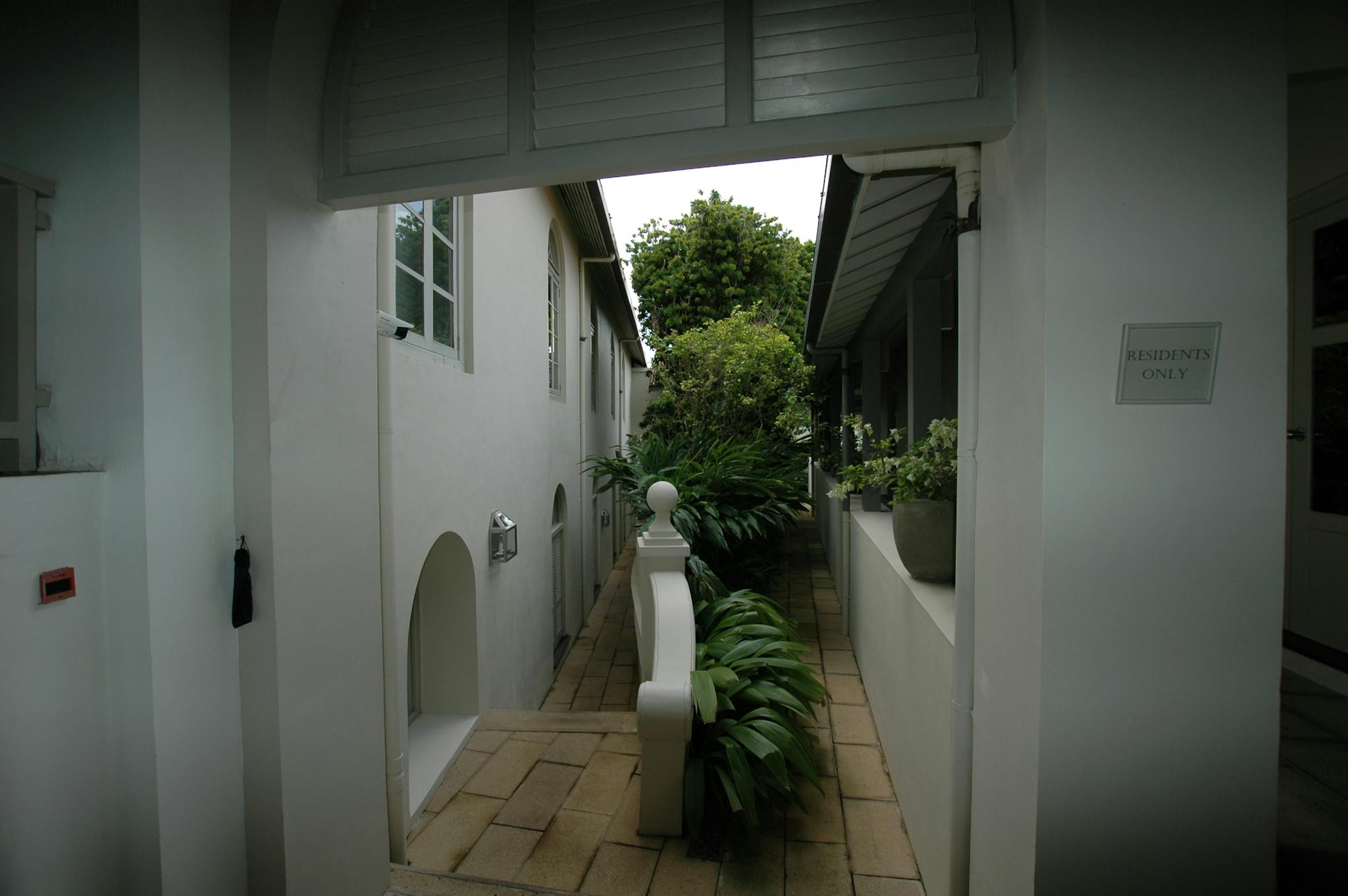 A tranquil residential walkway lined with plants and 'Residents Only' sign, exuding a serene atmosphere.