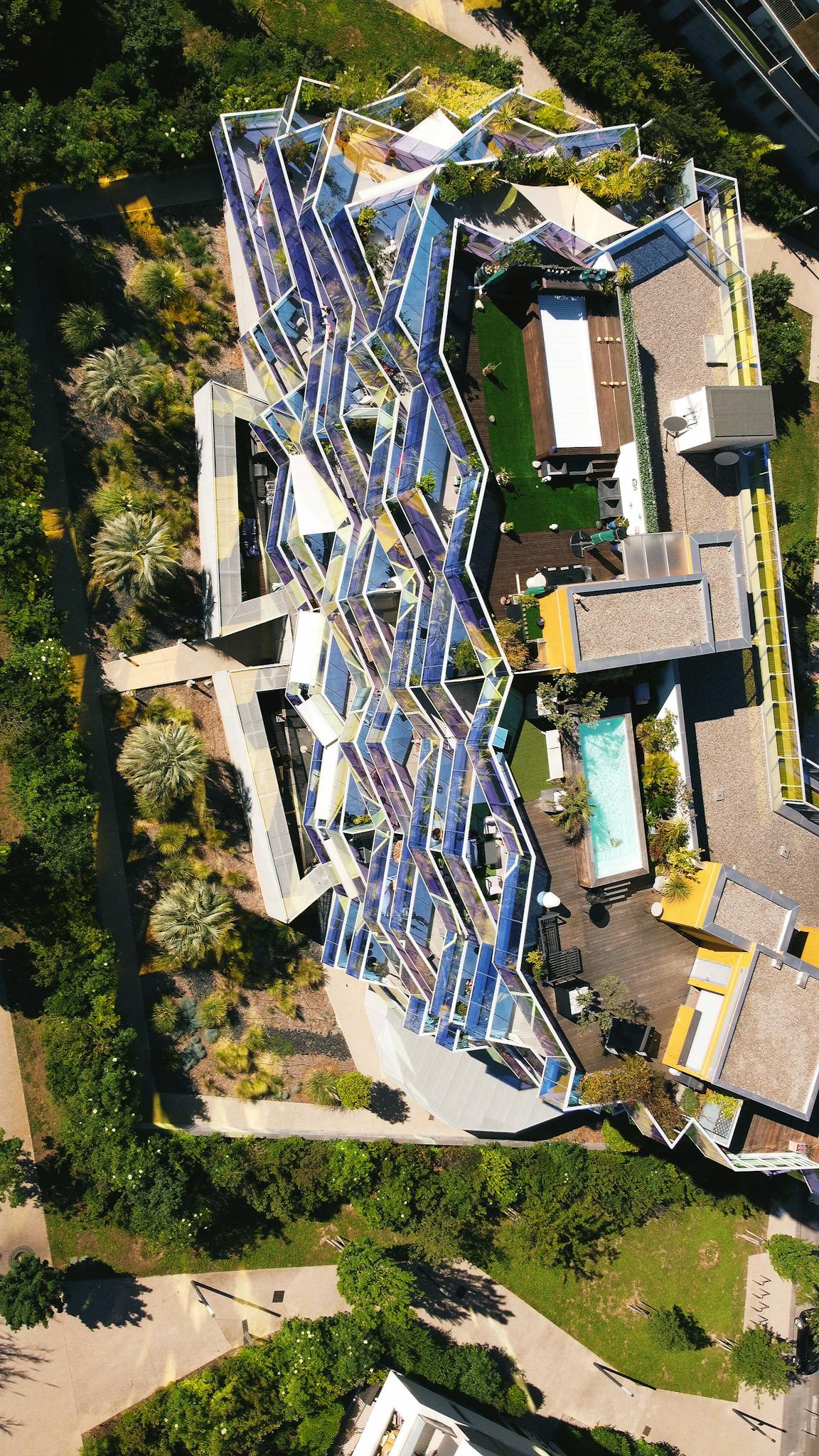 Aerial view of a modern residential building with unique architecture and rooftop pool.
