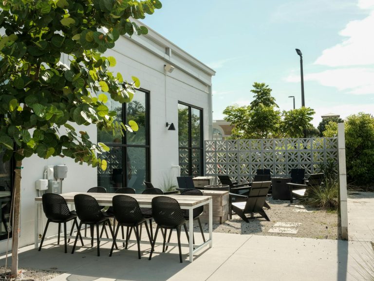 Contemporary outdoor patio with modern chairs and tables under clear sky.