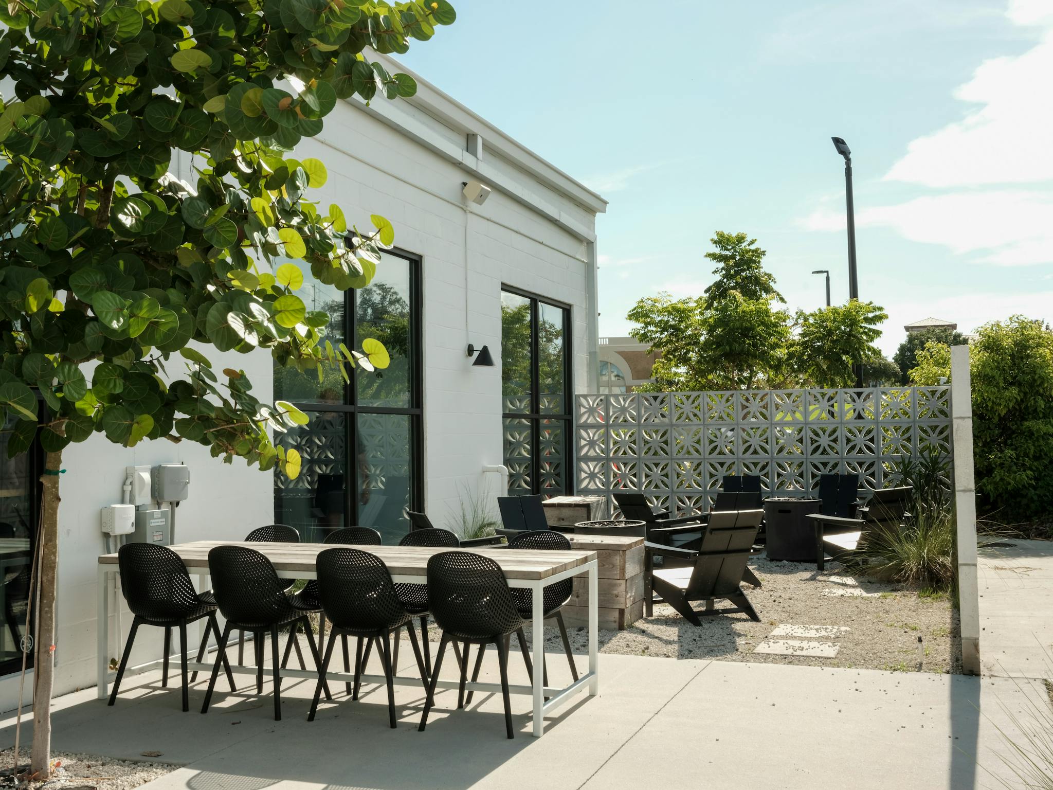 Contemporary outdoor patio with modern chairs and tables under clear sky.